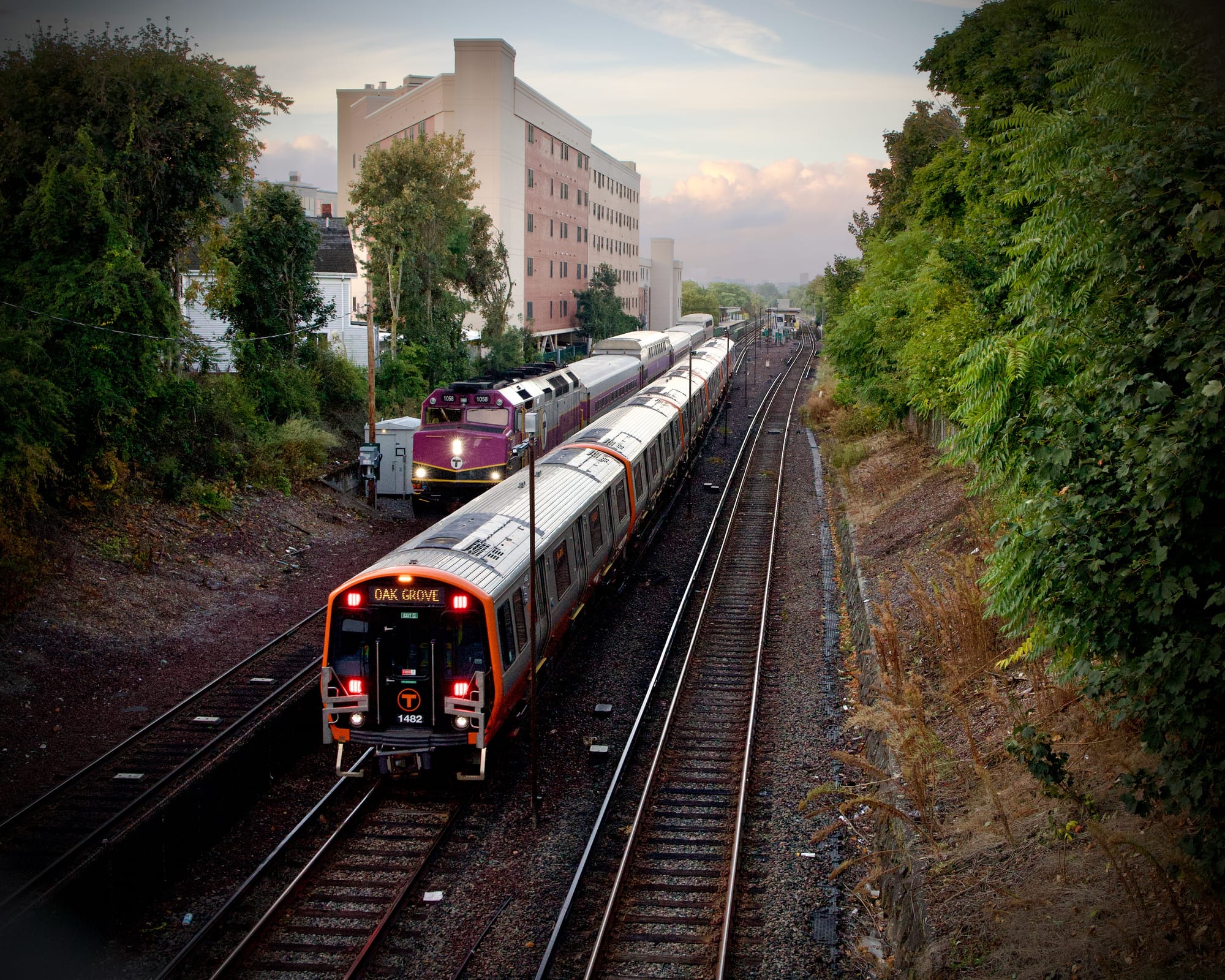 Two MBTA trains, one orange line and one commuter rail