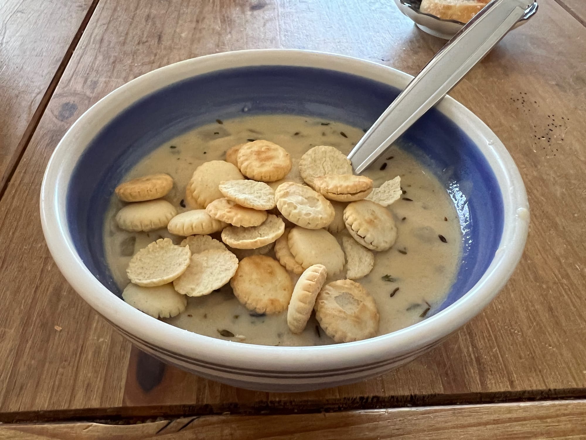 A bowl of homemade clam chowder with oyster crackers on top