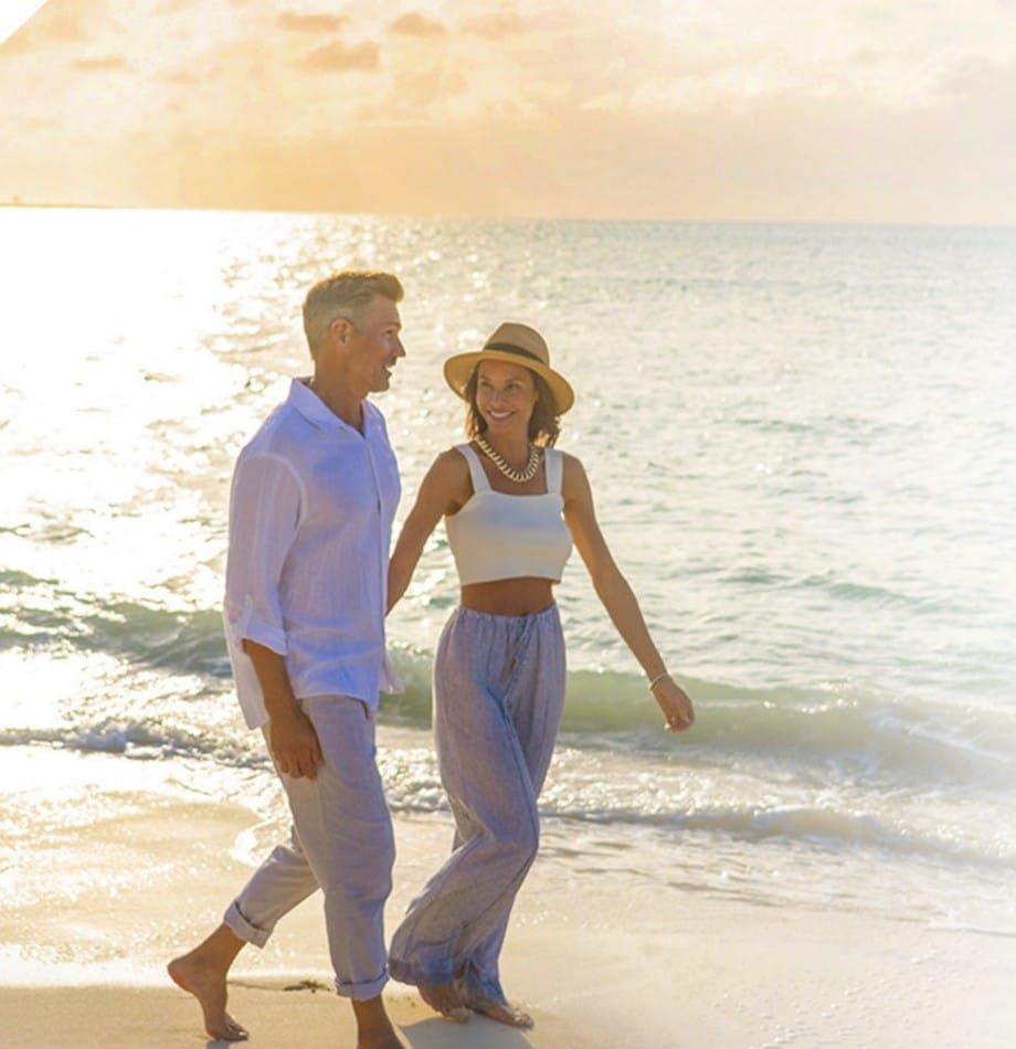 A couple walking along a white-sand beach at sunset on Nassau and Paradise Island, The Bahamas