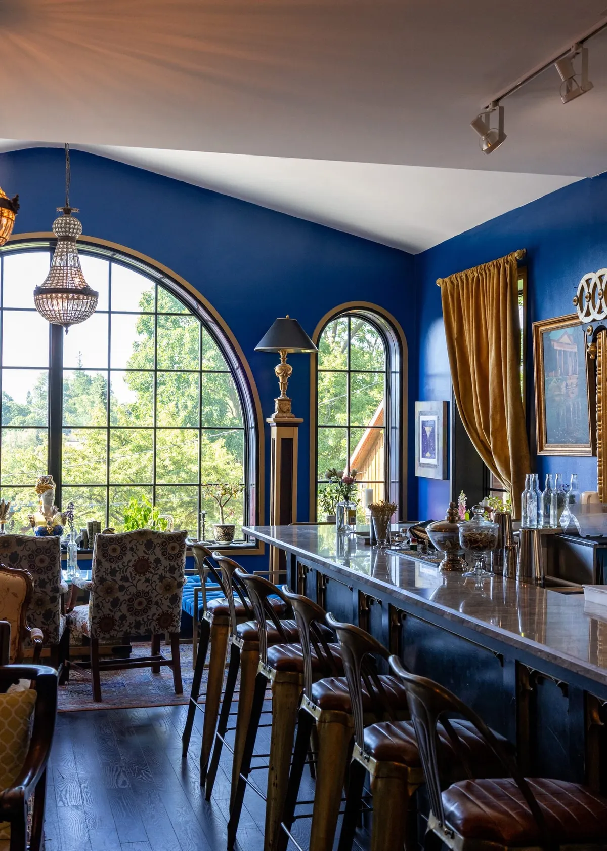 The Royal Room upstairs at Elora Distilling Co., with arched windows, a navy wall and a long bar lined with leather stools