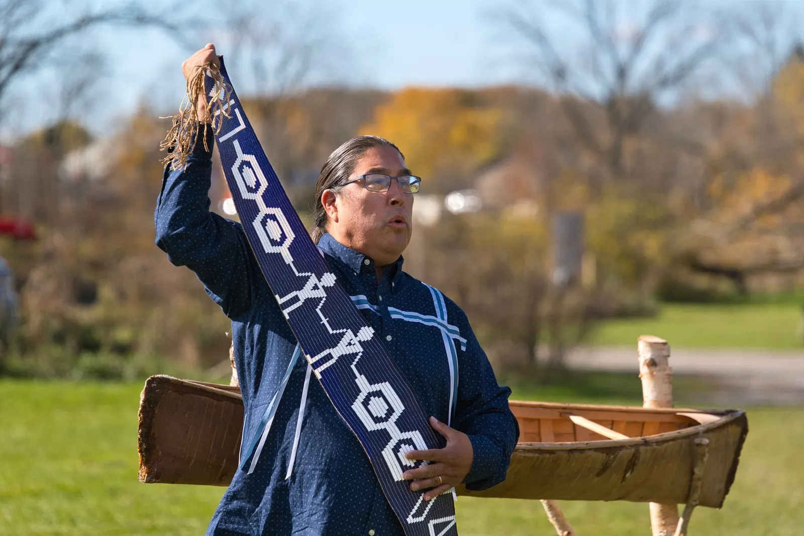 A knowledge carrier raises a wampum belt during ceremony