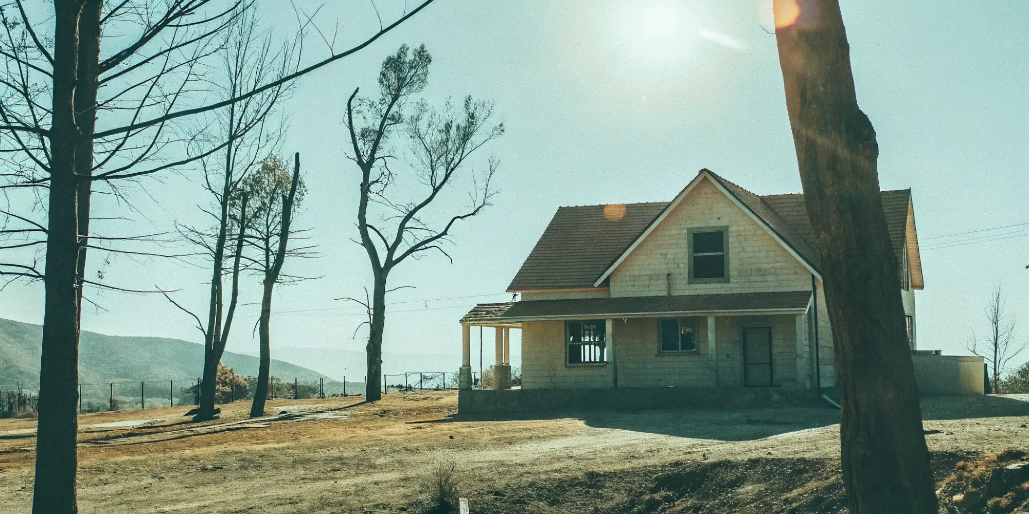 A home surrounded by scorched land, a clear example of wildfire risk and the need for insurance.
