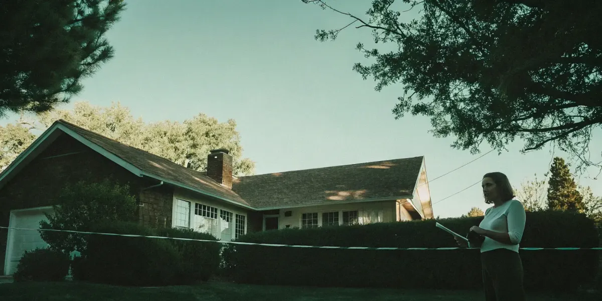 An insurance inspector with a clipboard evaluates a home's exterior for an inspection.