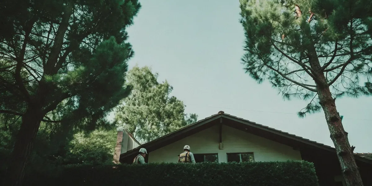 A professional performs a wildfire home assessment on a house surrounded by trees.