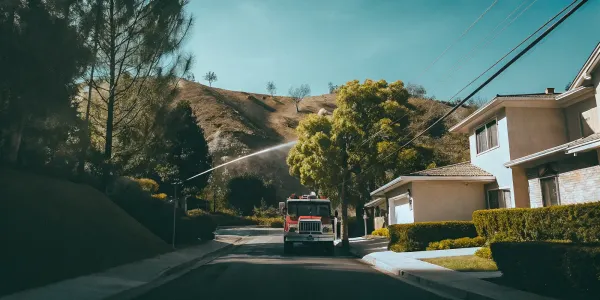 A fire truck conducts a wildfire safety inspection on a hillside for a property risk report.