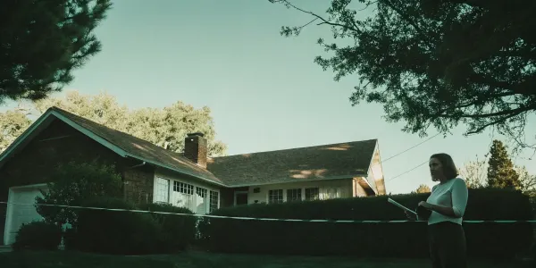 An insurance inspector with a clipboard evaluates a home's exterior for an inspection.