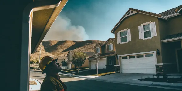Firefighter in a neighborhood with wildfire risk, a key reason for homeowners insurance non-renewal.