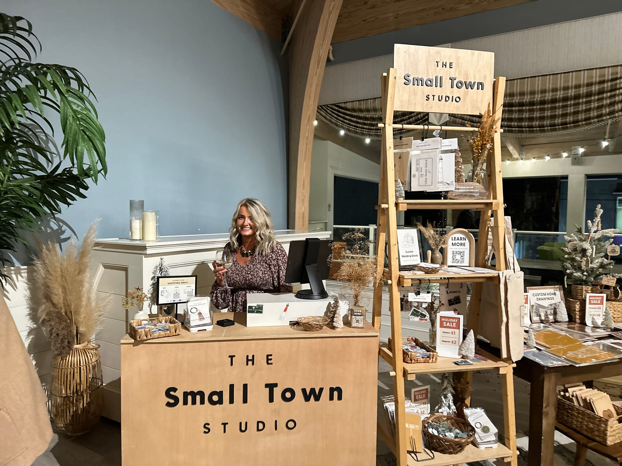 The Small Town Studio retail pop-up featuring a wooden display of illustrated souvenirs, home decor, and branded signage.