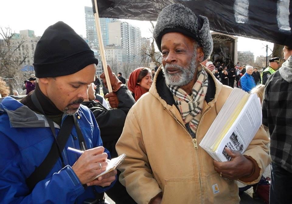 Yawu Miller interviews an activist during a protest.