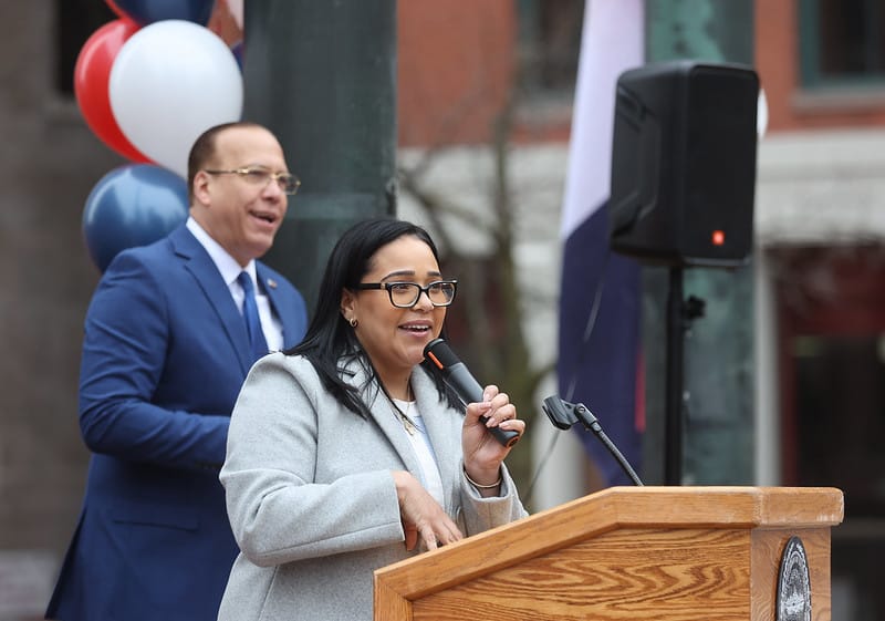 City Council candidate Alexandra Valdez speaks at a lectern during a recent Dominican flag raising at City Hall Plaza.