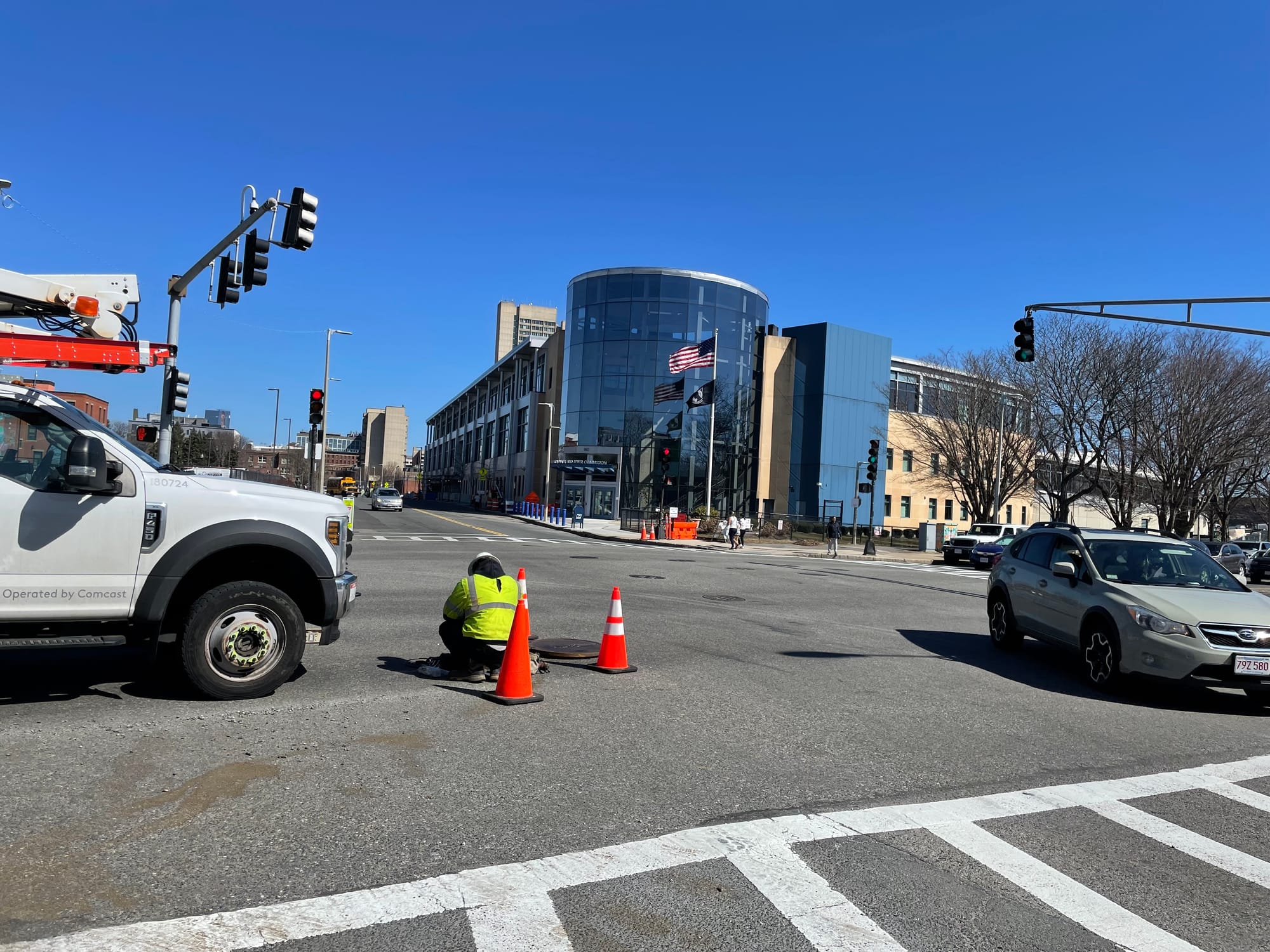 An Xfinity worker examines a utility hole on Melnea Cass Boulevard.