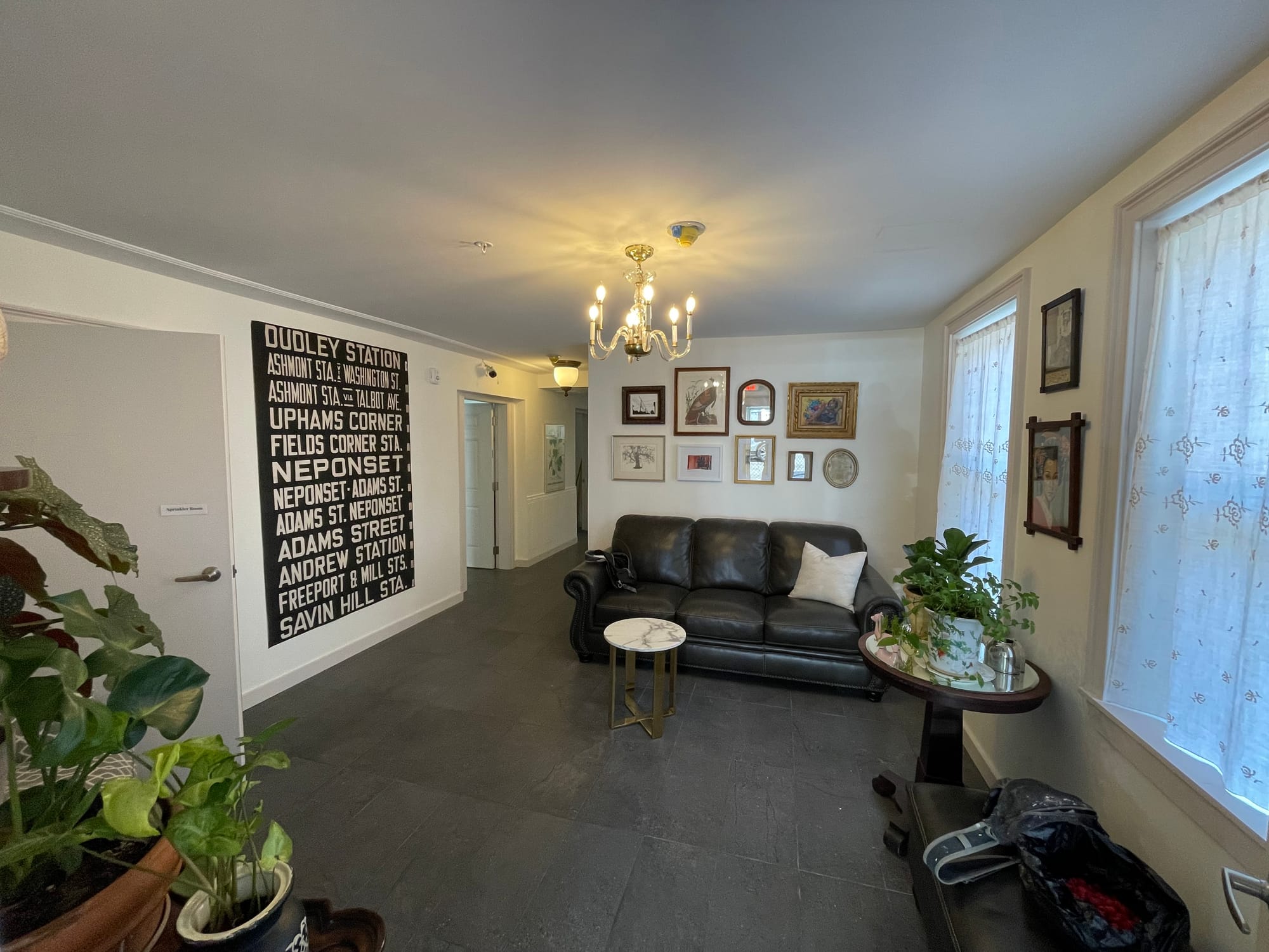 A common area at 141 Westville Street showing small tables, a couch and walls decorated with artwork.