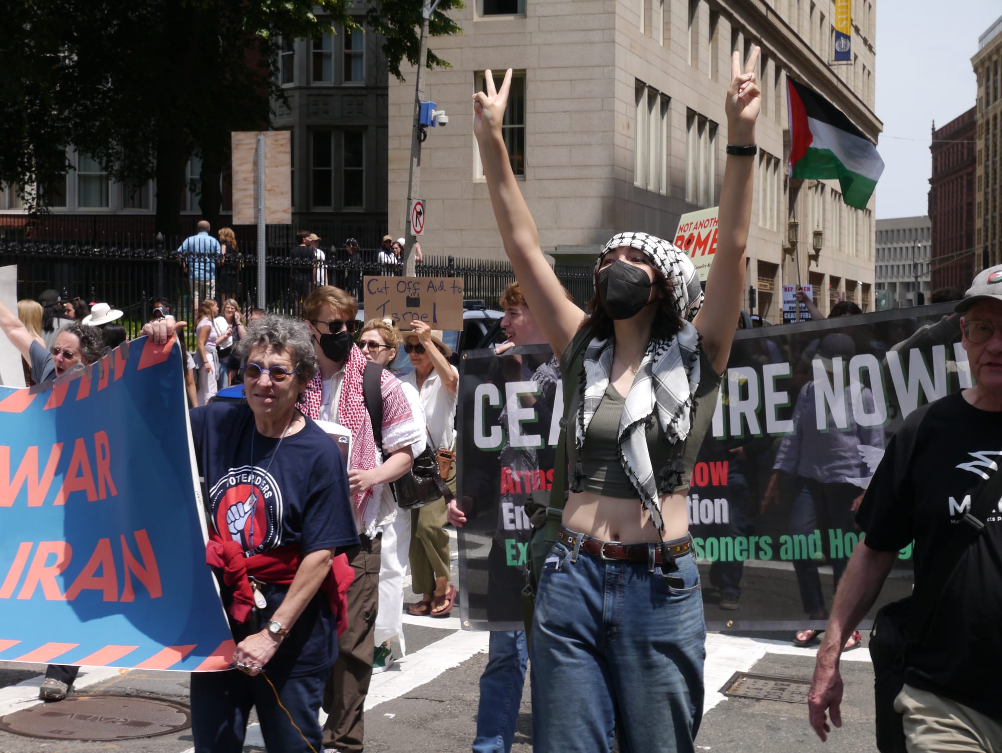A masked protestor flashes peace signs while marching on Tremont Street.