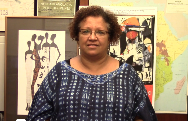 Nezi Brito, posing in front of posters of African art and a world map.