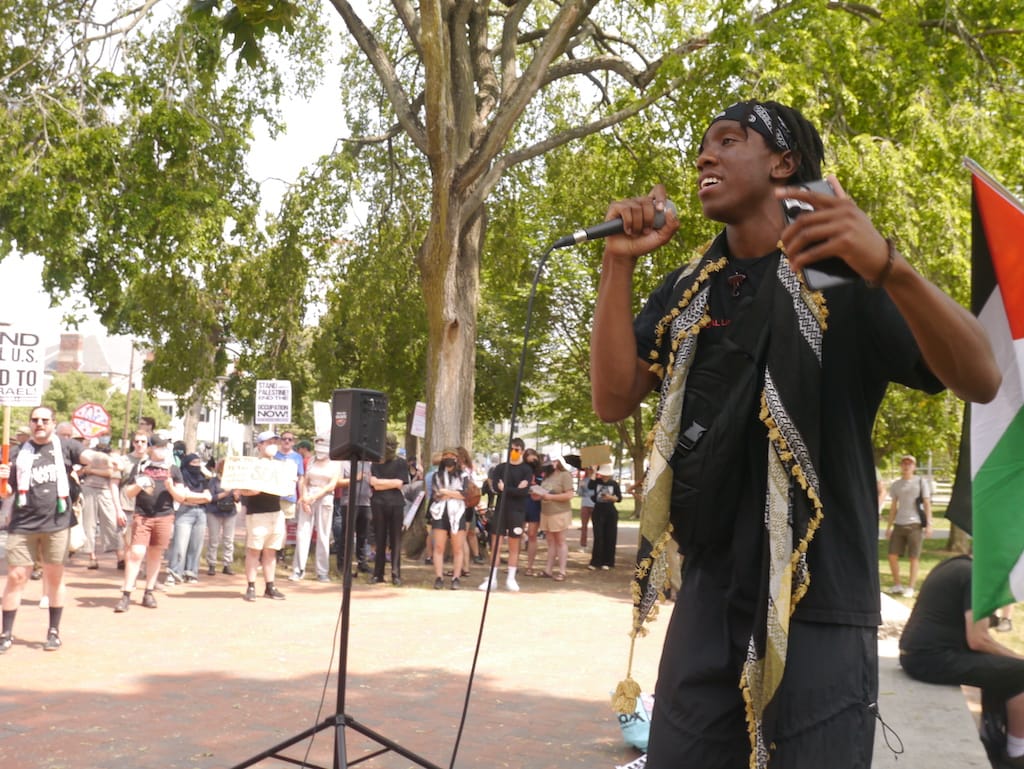 Holding a microphone, Kojo Acheampong addresses demonstrators on the Cambridge Common.