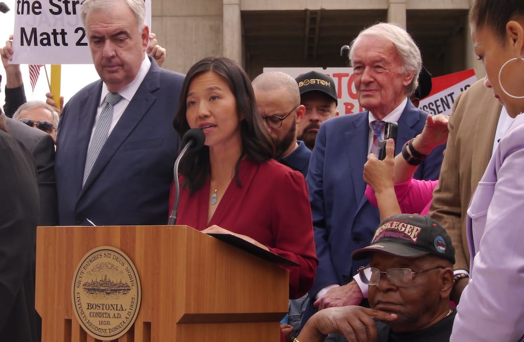 Mayor Michell wu speaks at podium on City Hall Plaza. Behind are former Police Commissioner Ed Davis and U.S. Sen. Ed Markey.