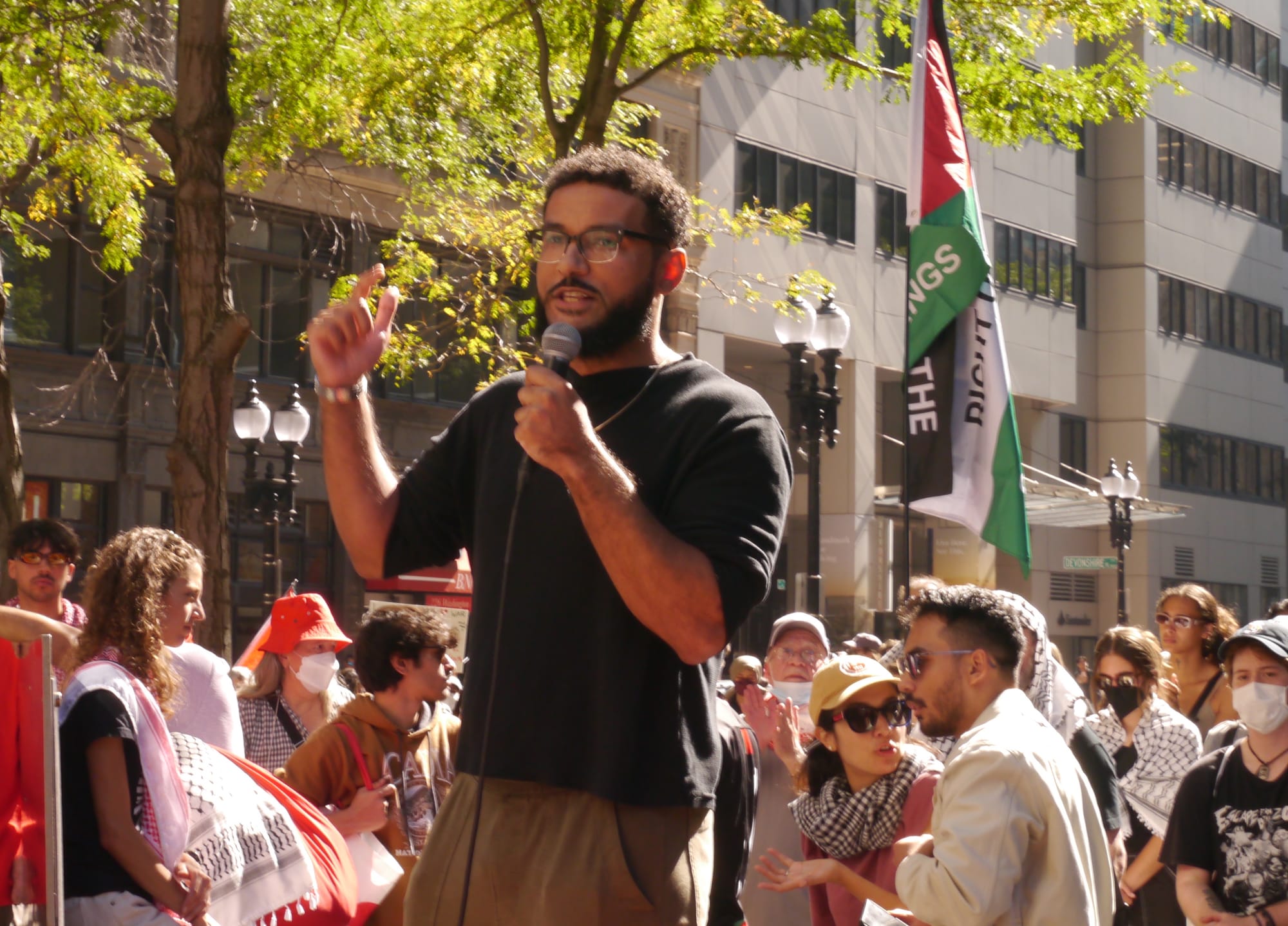 Activist Joe Tache speaks with a microphone as demonstrators gather at Washington and Court streets.
