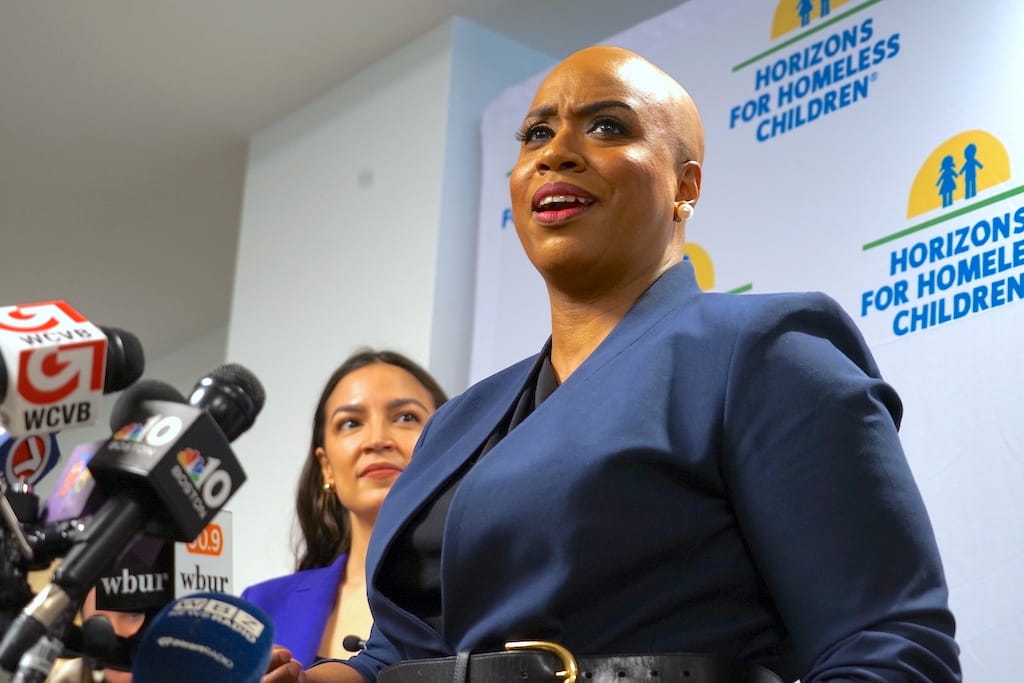 U.S. Rep. Ayanna Pressley addresses reporters as U.S. Rep. Alexandria Ocasio-Cortez looks on.