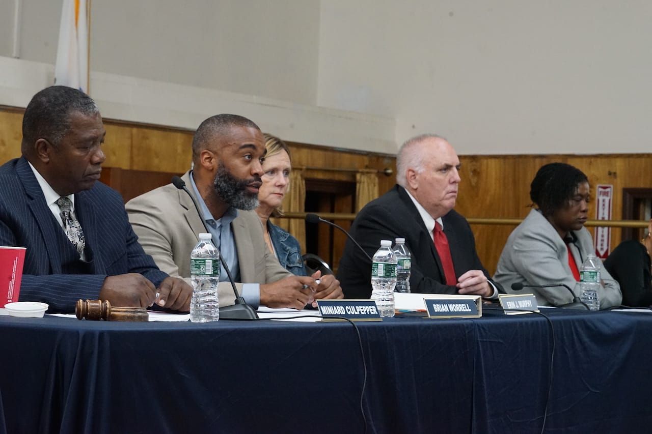 District 4 Councilor Brian Worrell, seated at a head table, speaks. Next to him, from left to right, are councilors Miniard Culpepper, Erin Murphy, Ed Flynn and Ruthzee Louijeune.