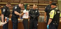 Police officers put zip tie hand cuffs on Better Budget Alliance member Vikiana Petit Homme as she is taken into custody in the Boston City Council's Iannella Chamber.