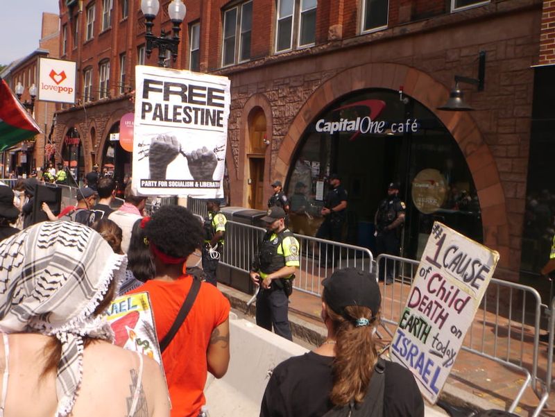 Demonstrators protest outside a Capital One bank branch on JFK Street in Harvard Square.