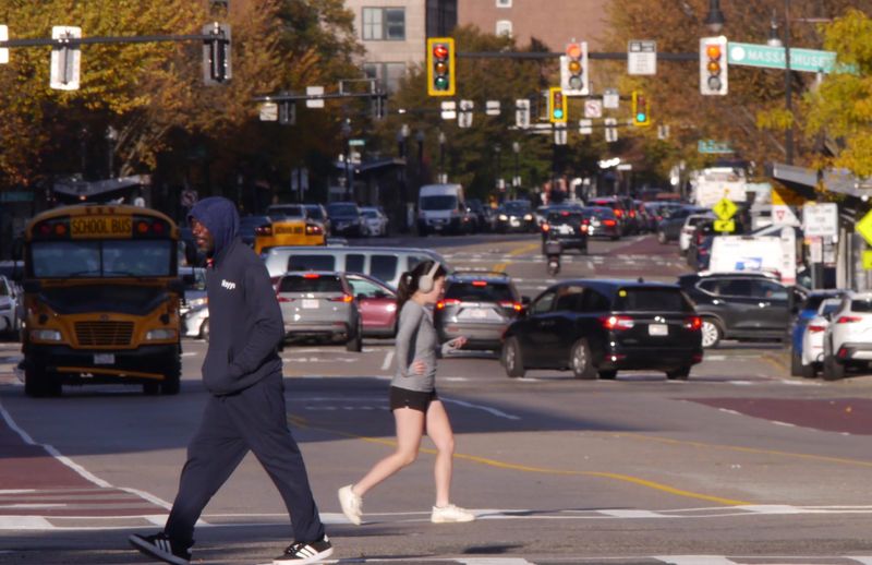 A Black man heads south west in the pedestrian crossing at Washington and Lenox streets while an Asian woman jogs in a northeast direction.