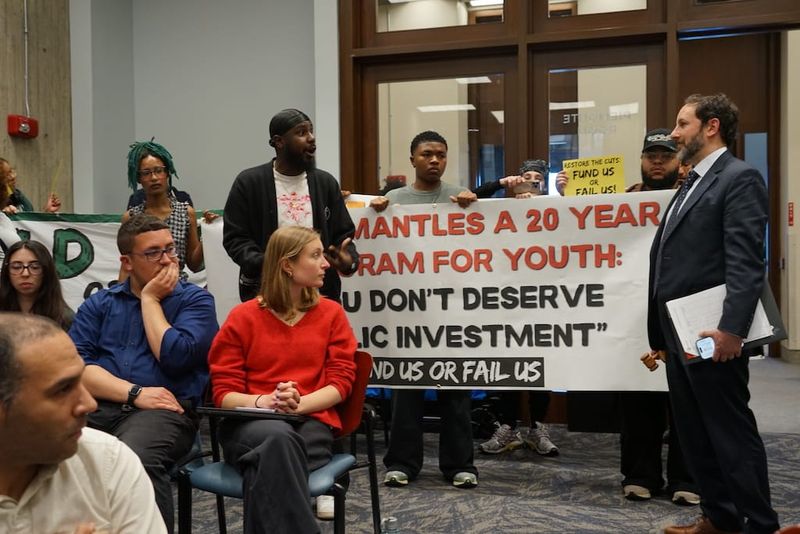 Activists question City Councilor Ben Webber in a protest that interrupted a working session in the Council's Piemonte Room.