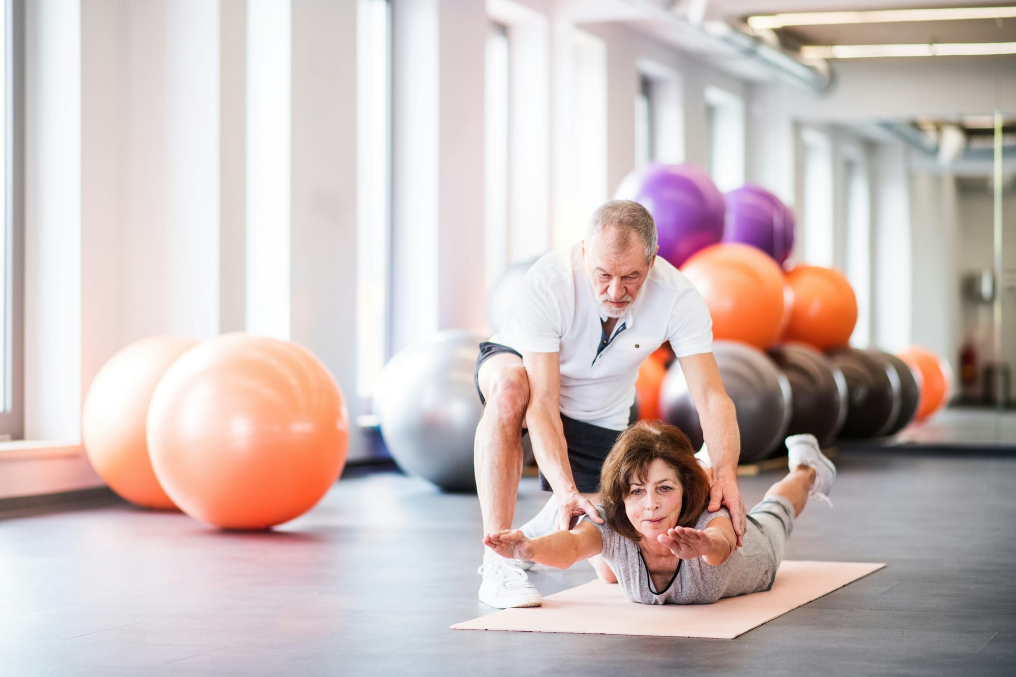 Frau macht aktive Bewegungstherapie, angeleitet durch Physiotherapeut.