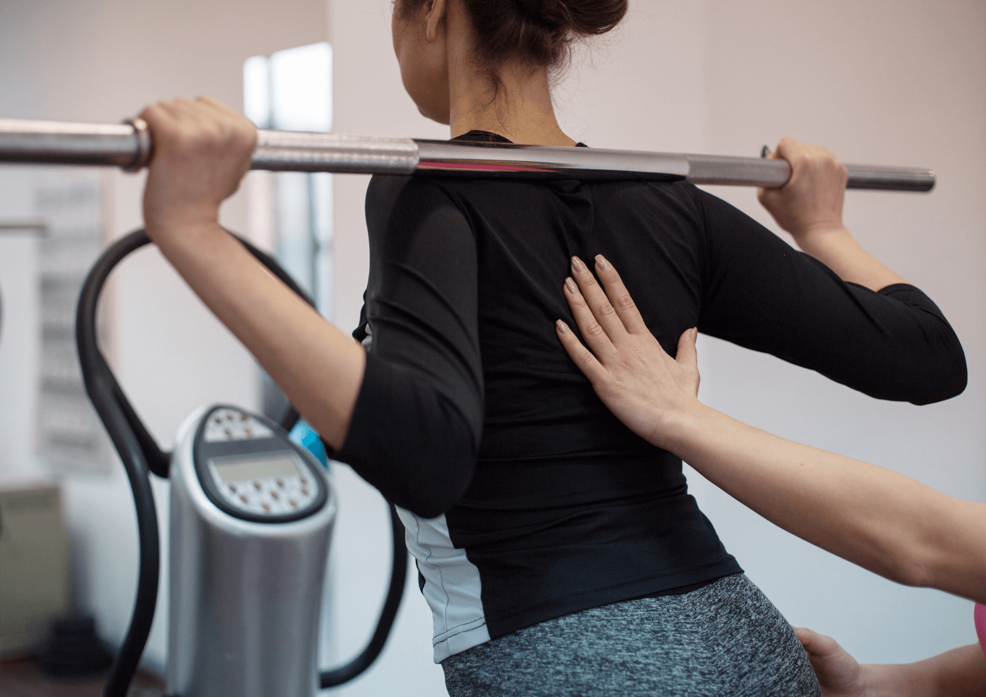 Woman is doing weighted exercise to help with mobility. Physiotherapist is supporting her.