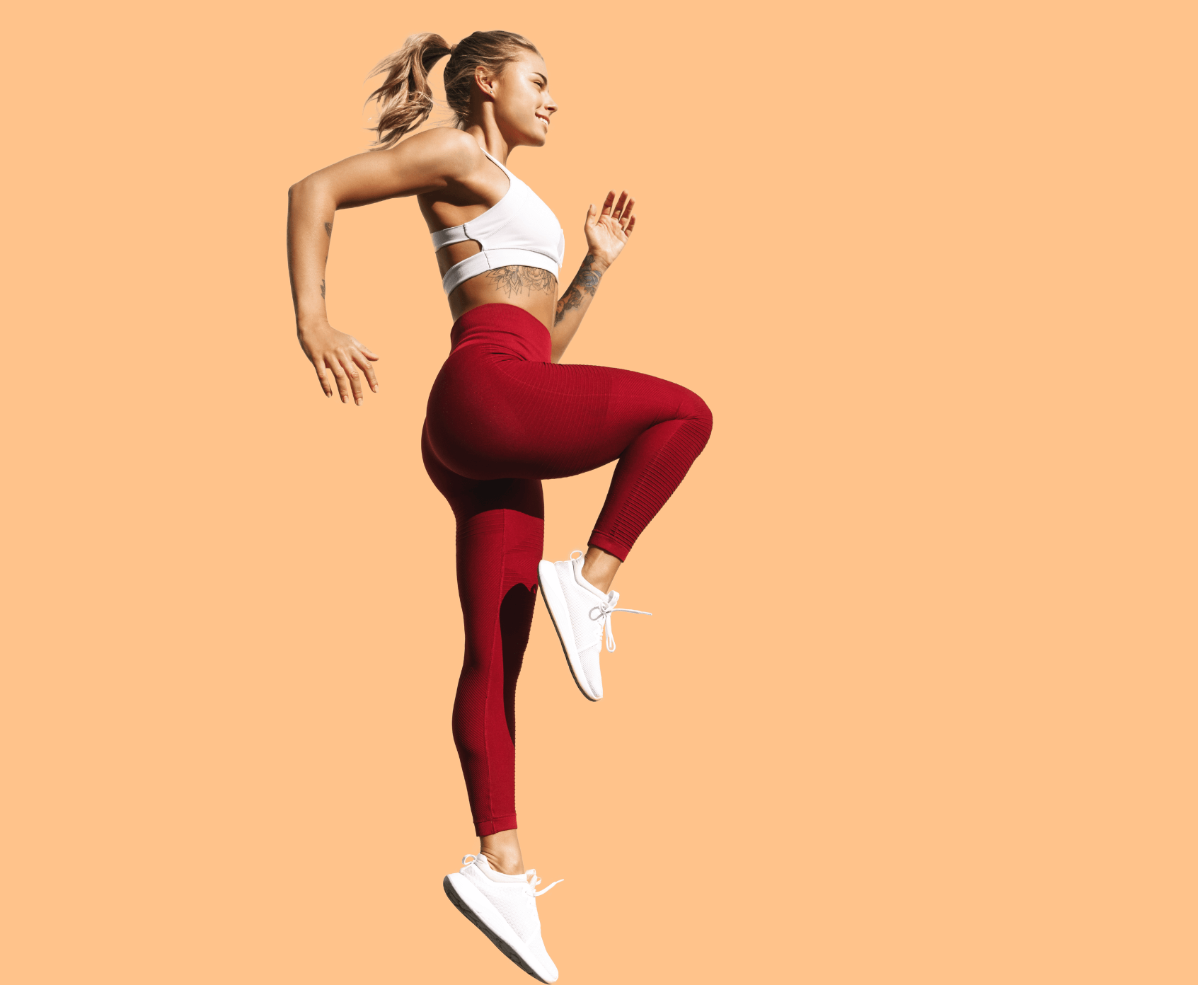 Junge Frau mit Tattoos macht Cardio Übungen.