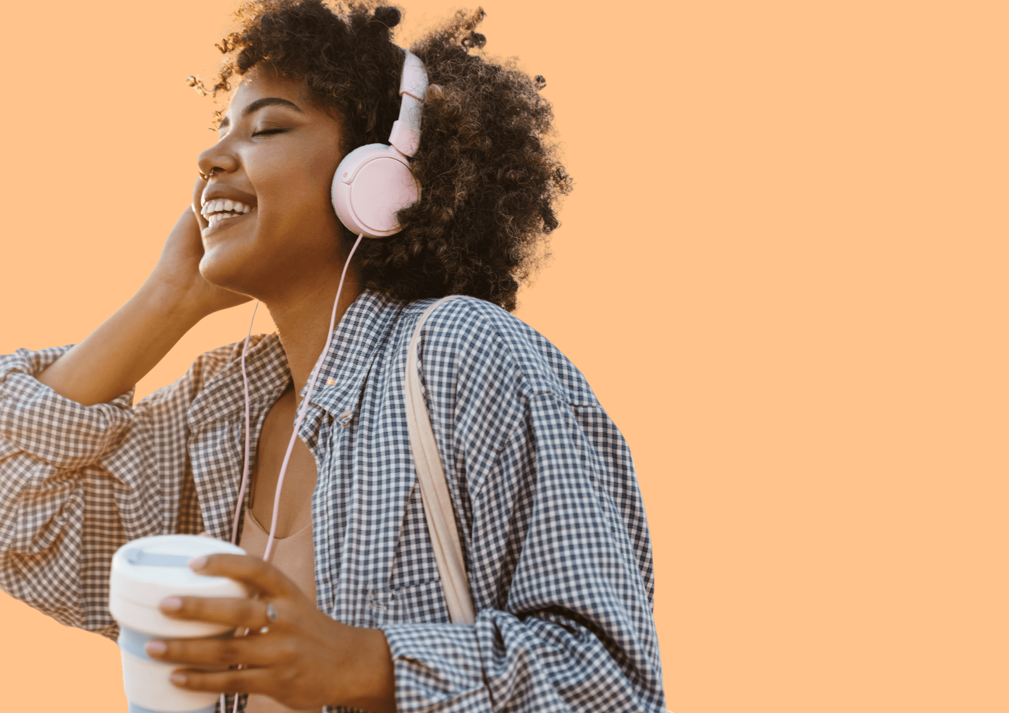 Frau mit Locken und Kopfhörern hört lachend Musik. Oranger Hintergrund.