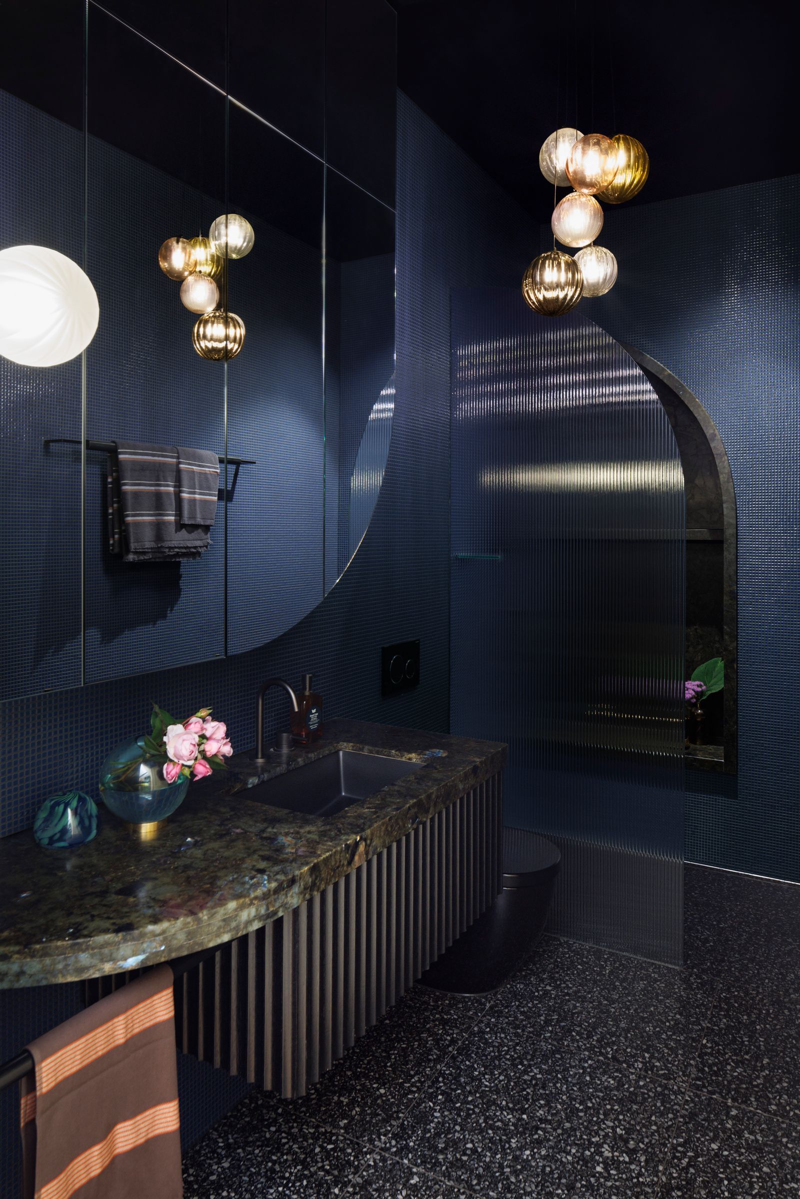 shared bathroom, awTiara House by FMD Architects. New shared bathroom featuring curved forms, inky blue tiling, speckled terrazzo, luminous granite and reeded glass. 