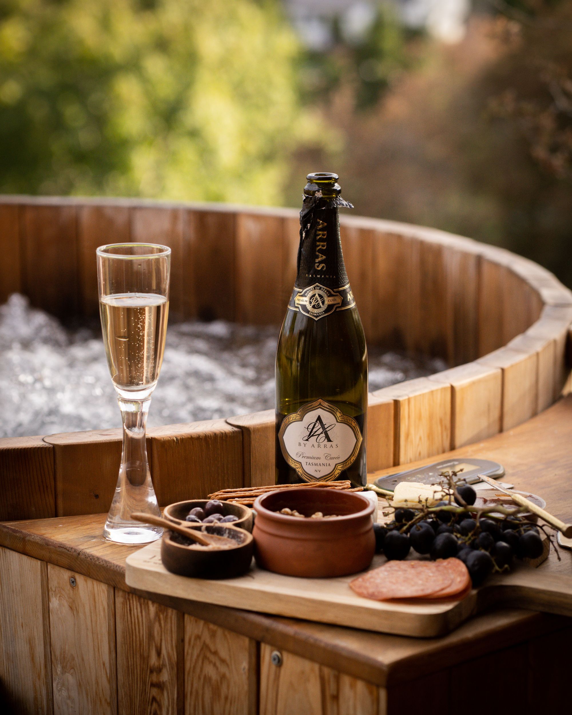 The Eco Cabin Tasmania by Wild Life Environmental. Detailed view of hot tub and charcuterie board and champagne.