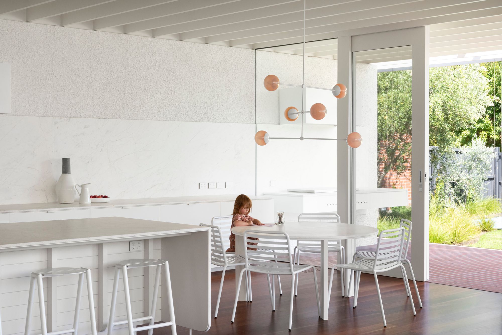 Elwood House by AM Architecture showing interior view of dining table with feature pendant light over