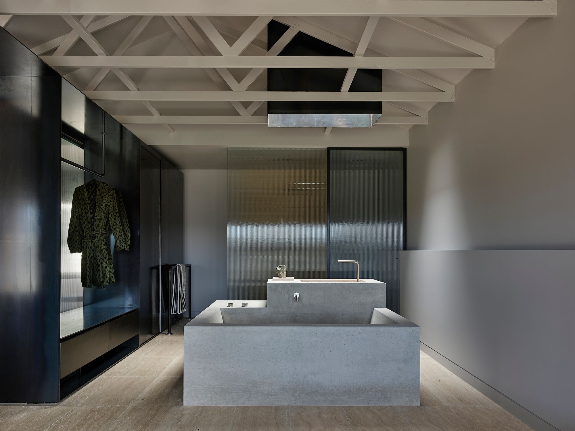 Bassano by Tom Robertson Architects showing an interior shot of the bathroom with a feature concrete bathtub with a skylight above