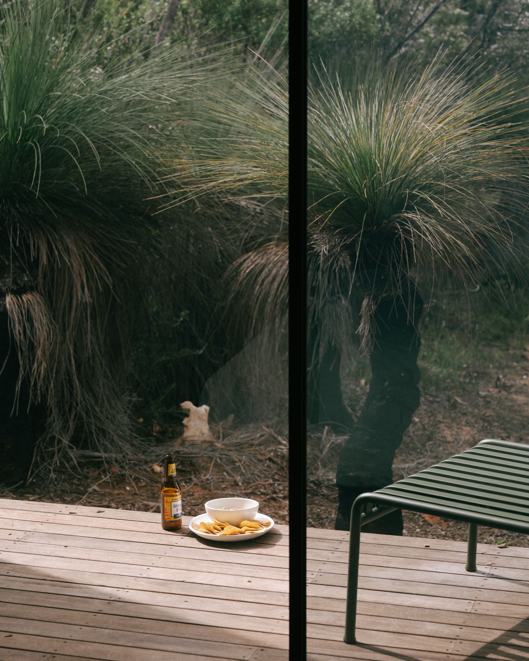 A view of the timber deck at DEN PLACE showing a beer and a bowl of chips on the deck