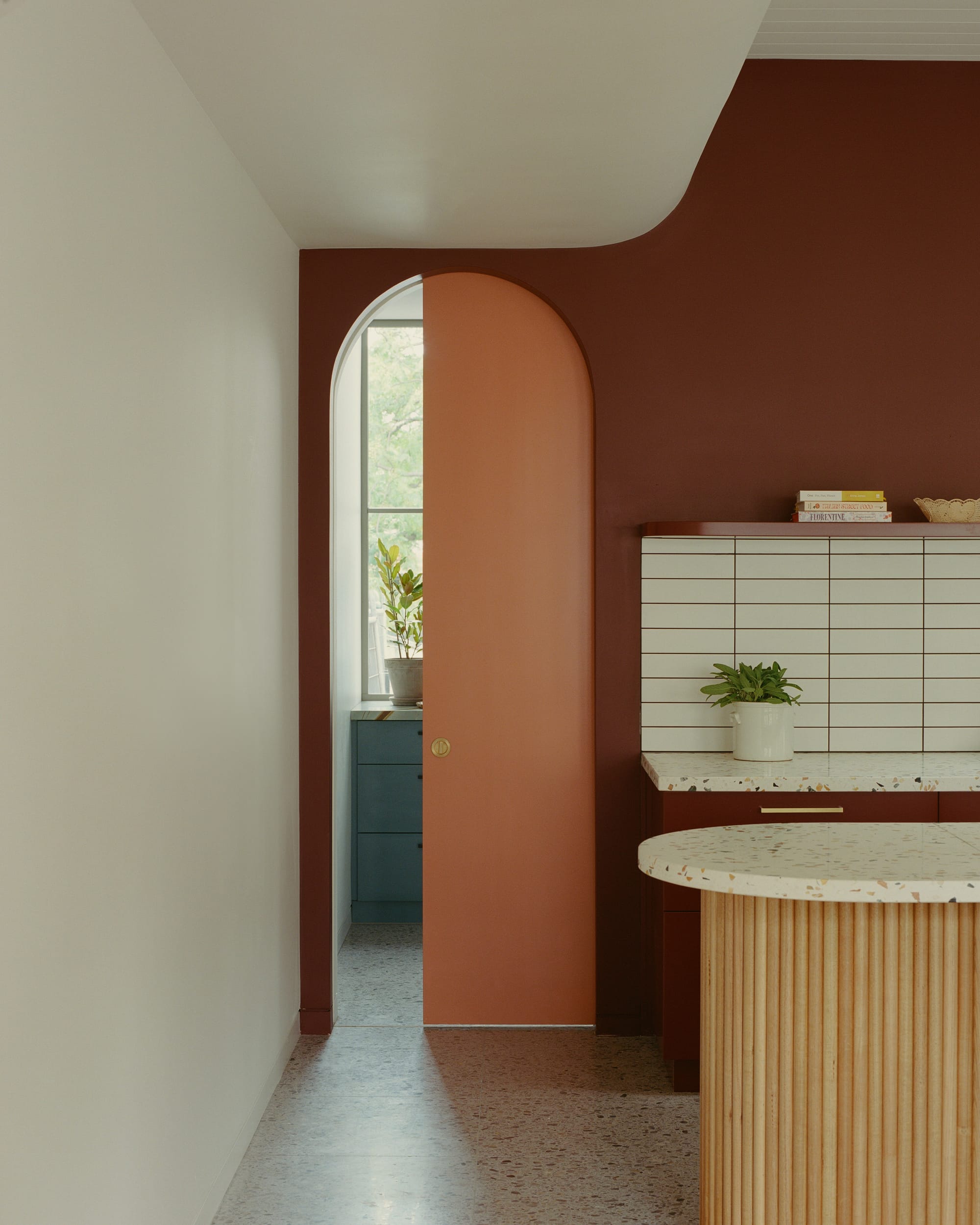 The image shows a modern bathroom with a free-standing bathtub, wooden floor mat, white subway tiles, and a large window that reveals a forest view.