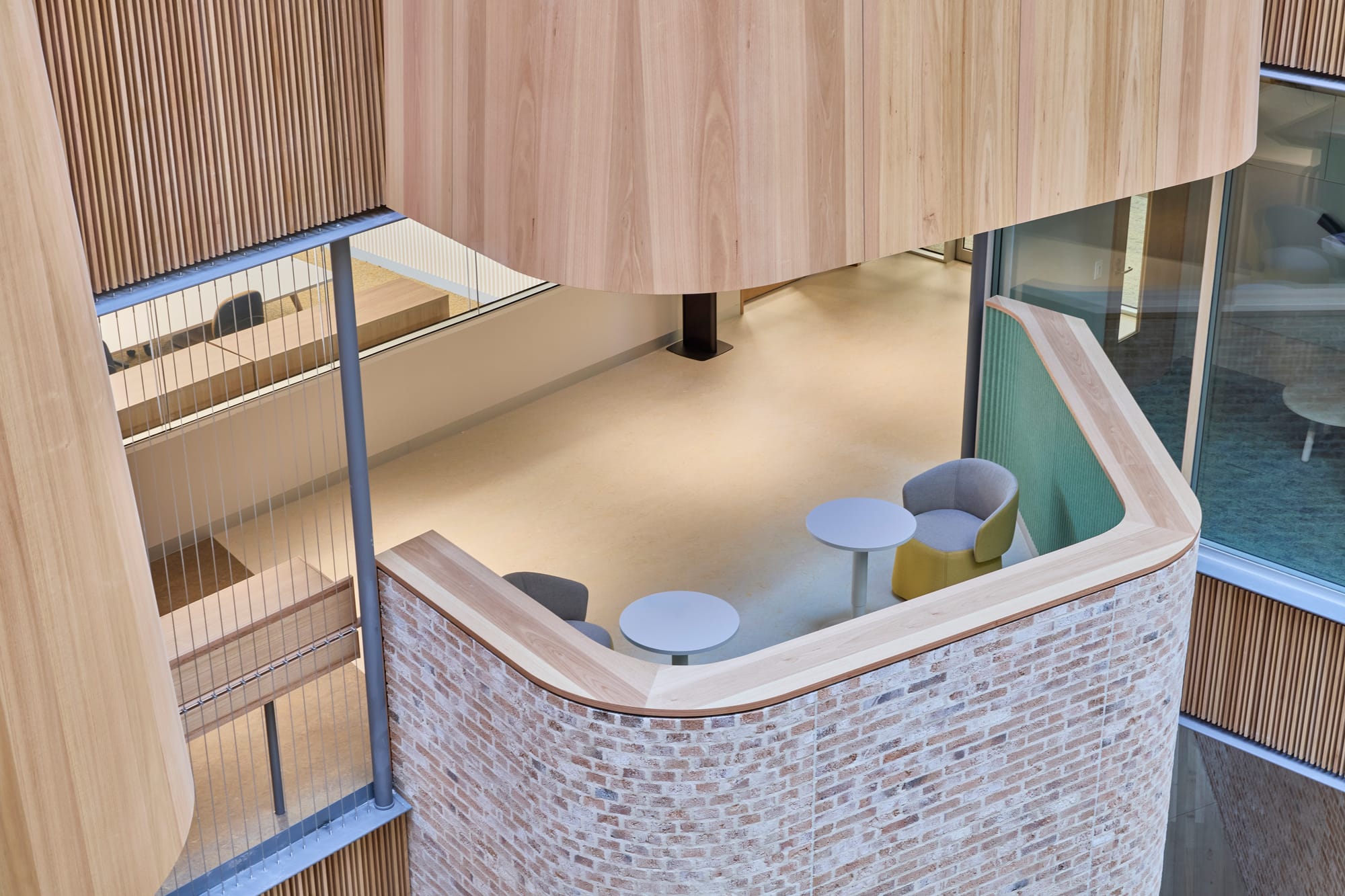 Tasmanian Timber: River's Edge. Photography: Dave Groves.A view inside a modern glass enclosure within a building, revealing a display of various items. The enclosure is framed with light wood, complementing the wooden floor, and offers visibility from multiple angles. This setup appears to function as an exhibition or showcase space, designed to integrate seamlessly with the surrounding interior architecture.