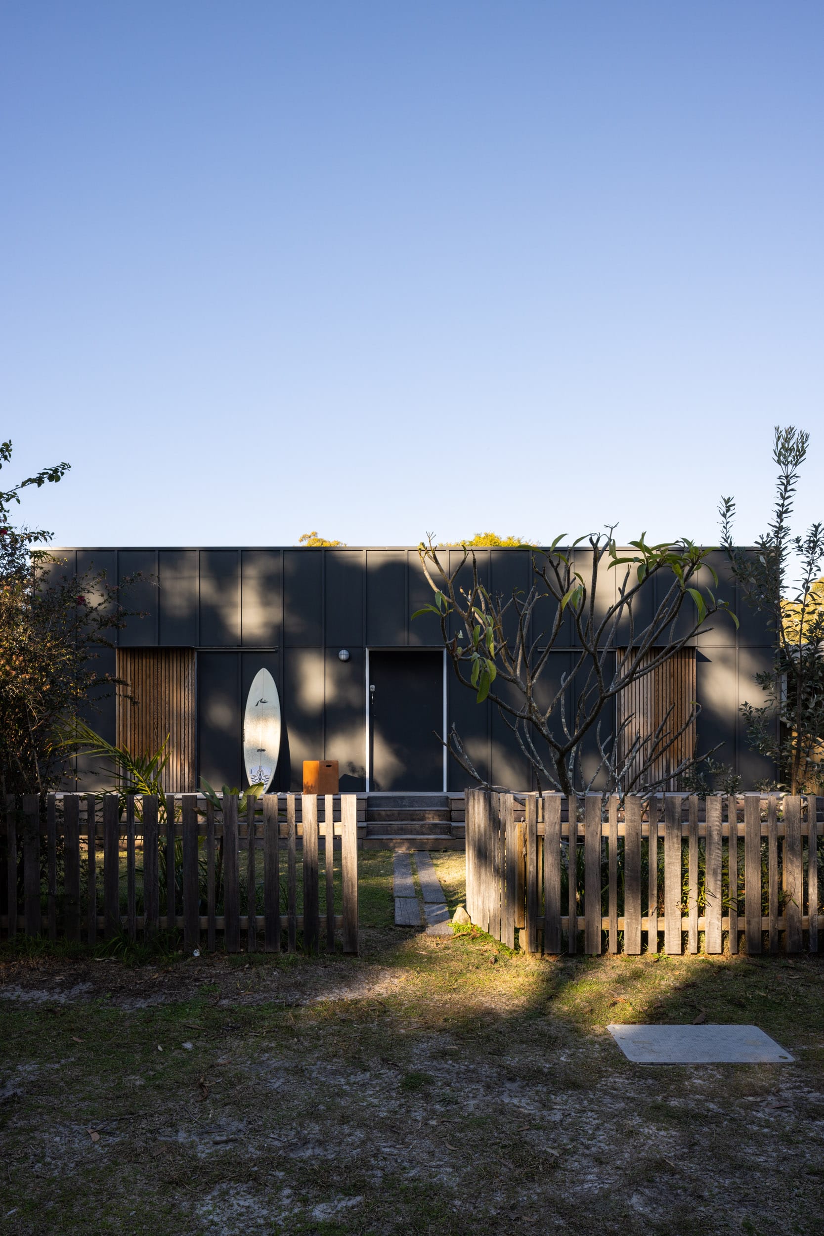 Drip-Dry House by Marker Architecture & Design. The front elevation of this beach house in Australia showing a surfboard leaning up against a wall