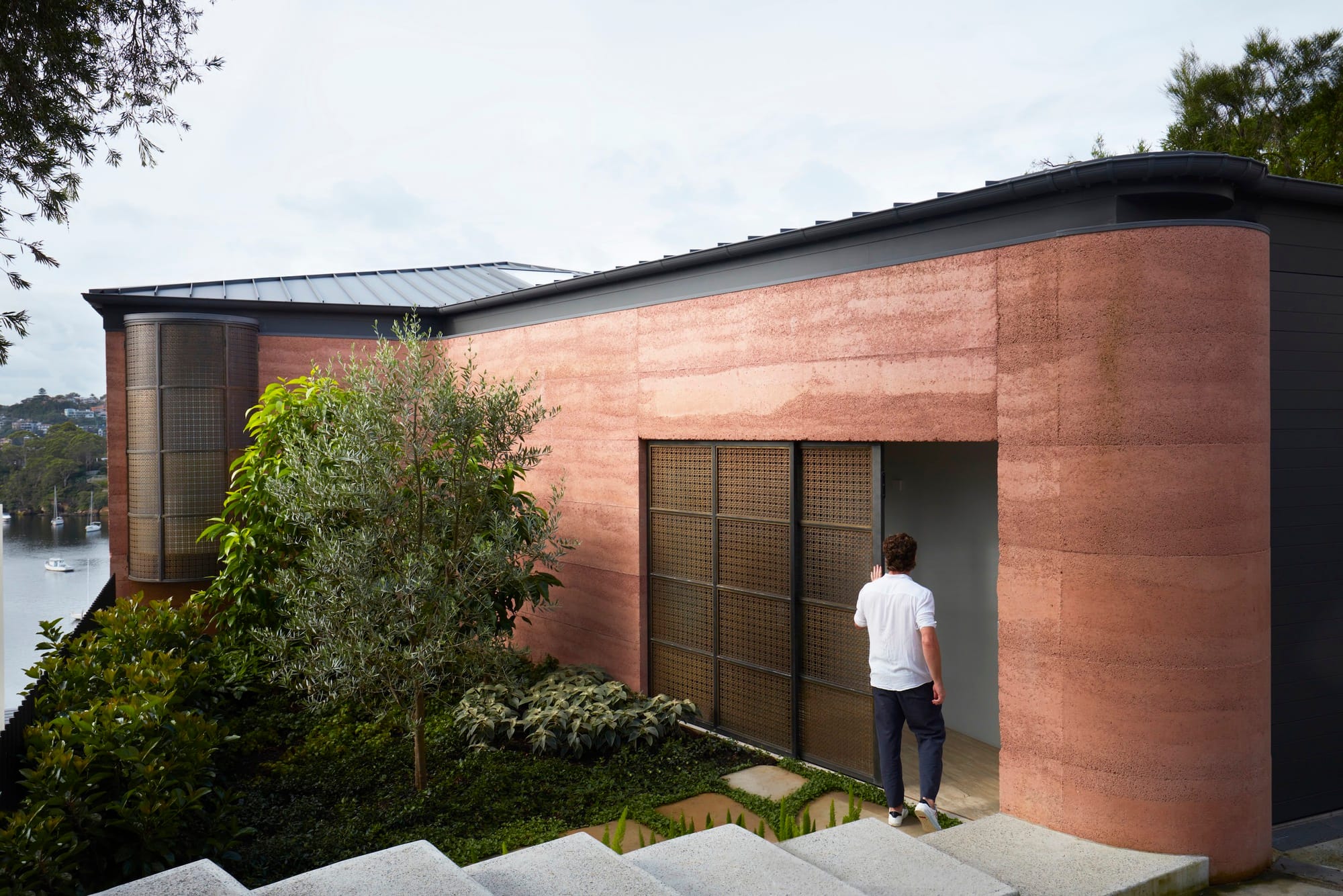 Earthship House by Luigi Rosselli Architects showing entry to the rammed earth house looking over Sydney Harbour