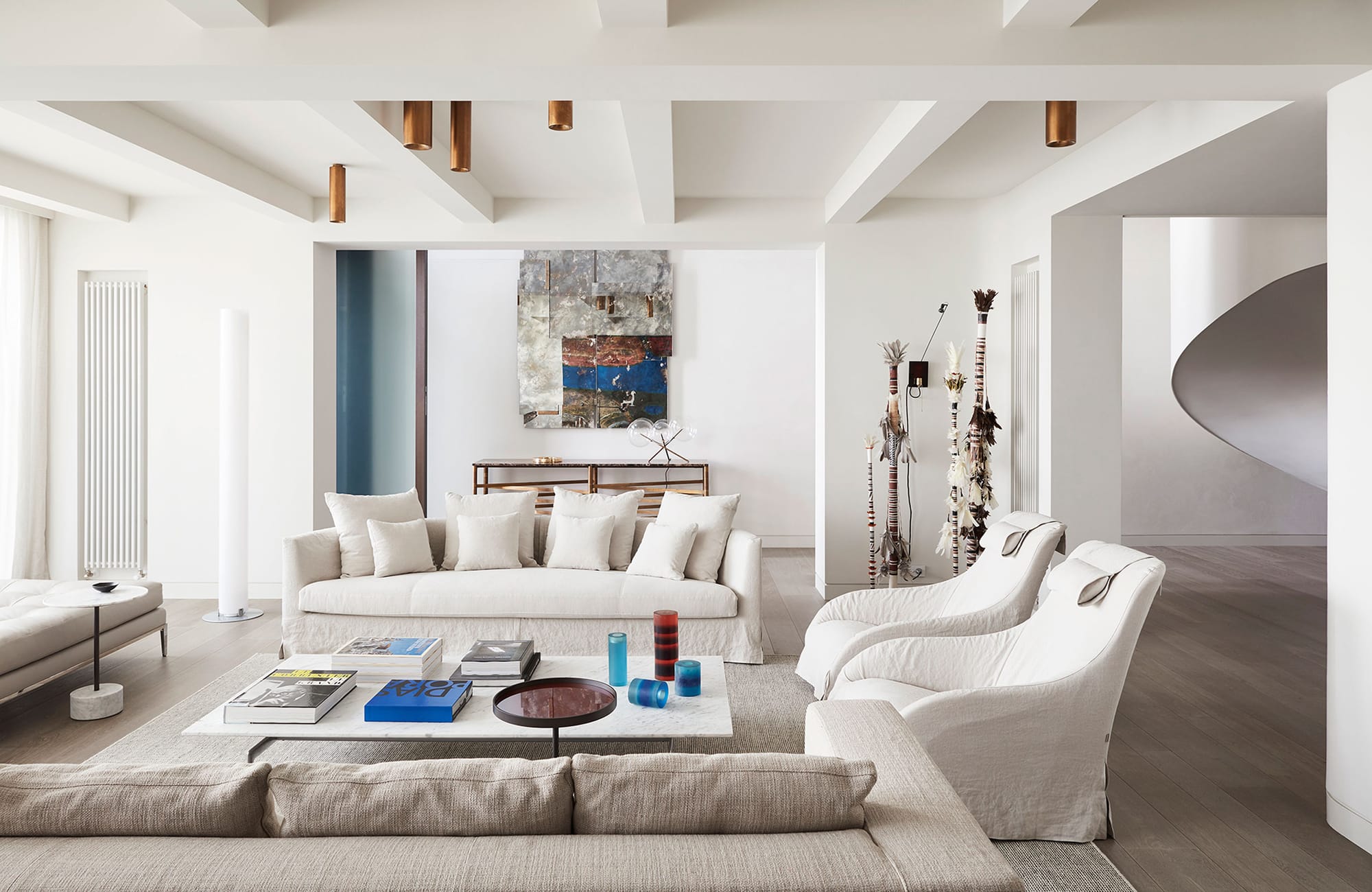 Arc Side by Jolson. Photography by Lucas Allen. Landscape image of residential living space. Tall white walls and ceilings, American Oak timber floors. Plush white couches. Neutral cabinetry along wall. Contemporary, organic coffee table. 