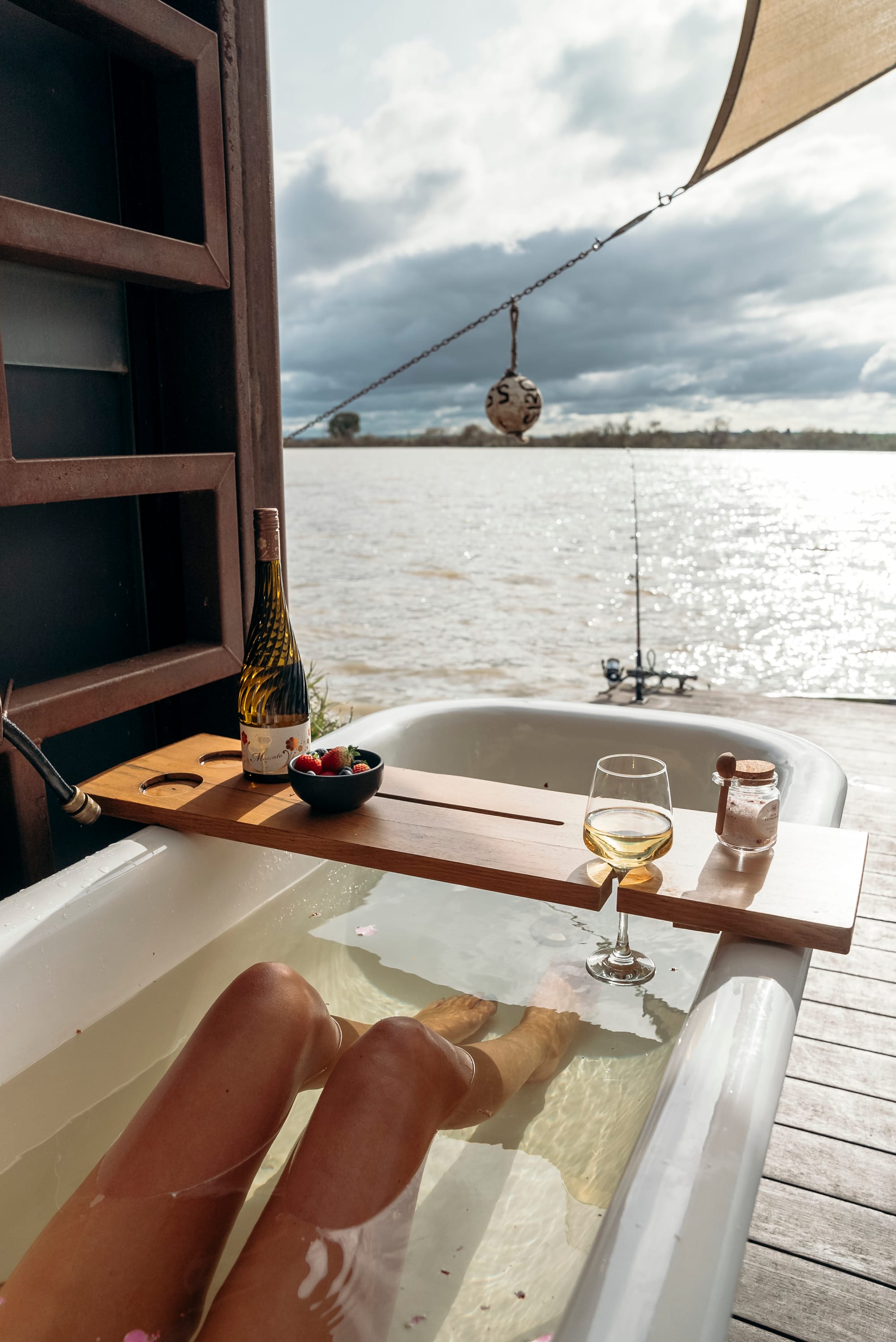 Bill's Boathouse. An exterior shot showing a woman in the outdoor bath looking over the river.