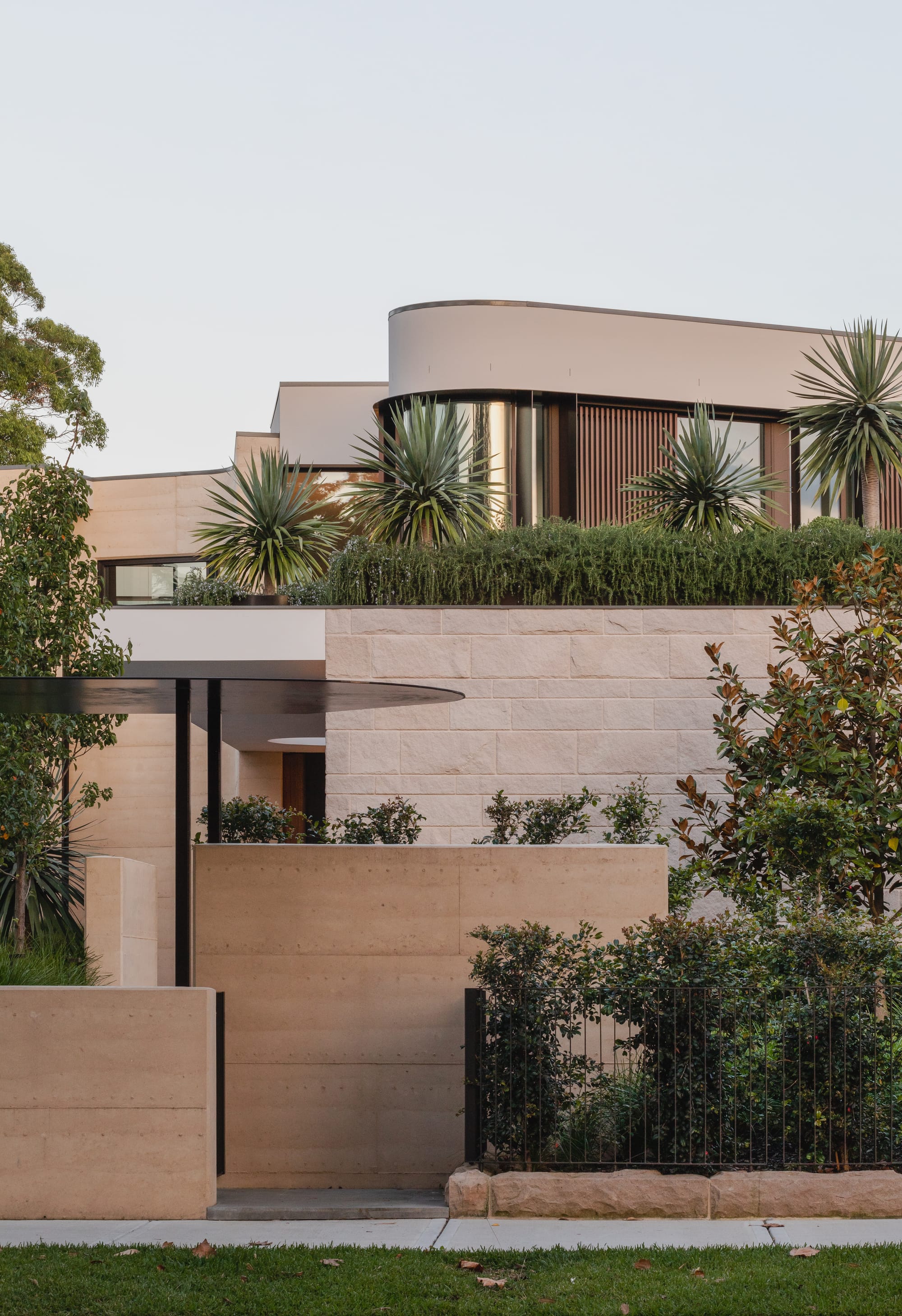 Kenneth Street by Design Studio Group showing an exterior view of the front showing the sandstone and rammed earth walls