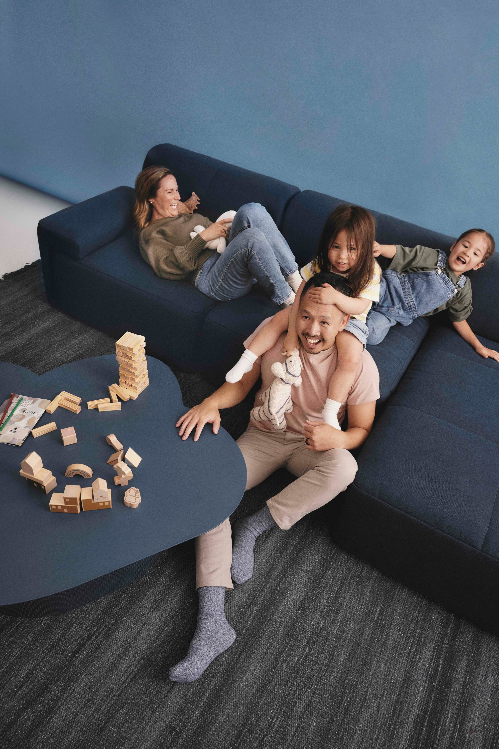 Eva Everyday Sofa. Copyright of Eva. Family of four playing on navy modular lounge. 