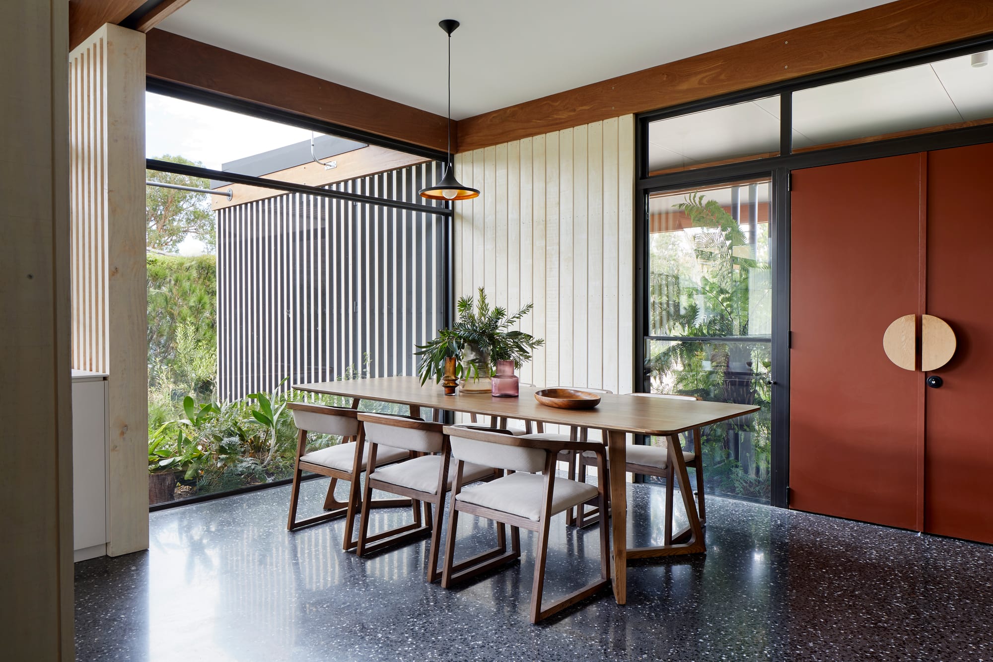 An interior shot of the dining room with a small pendant over and a large red front door
