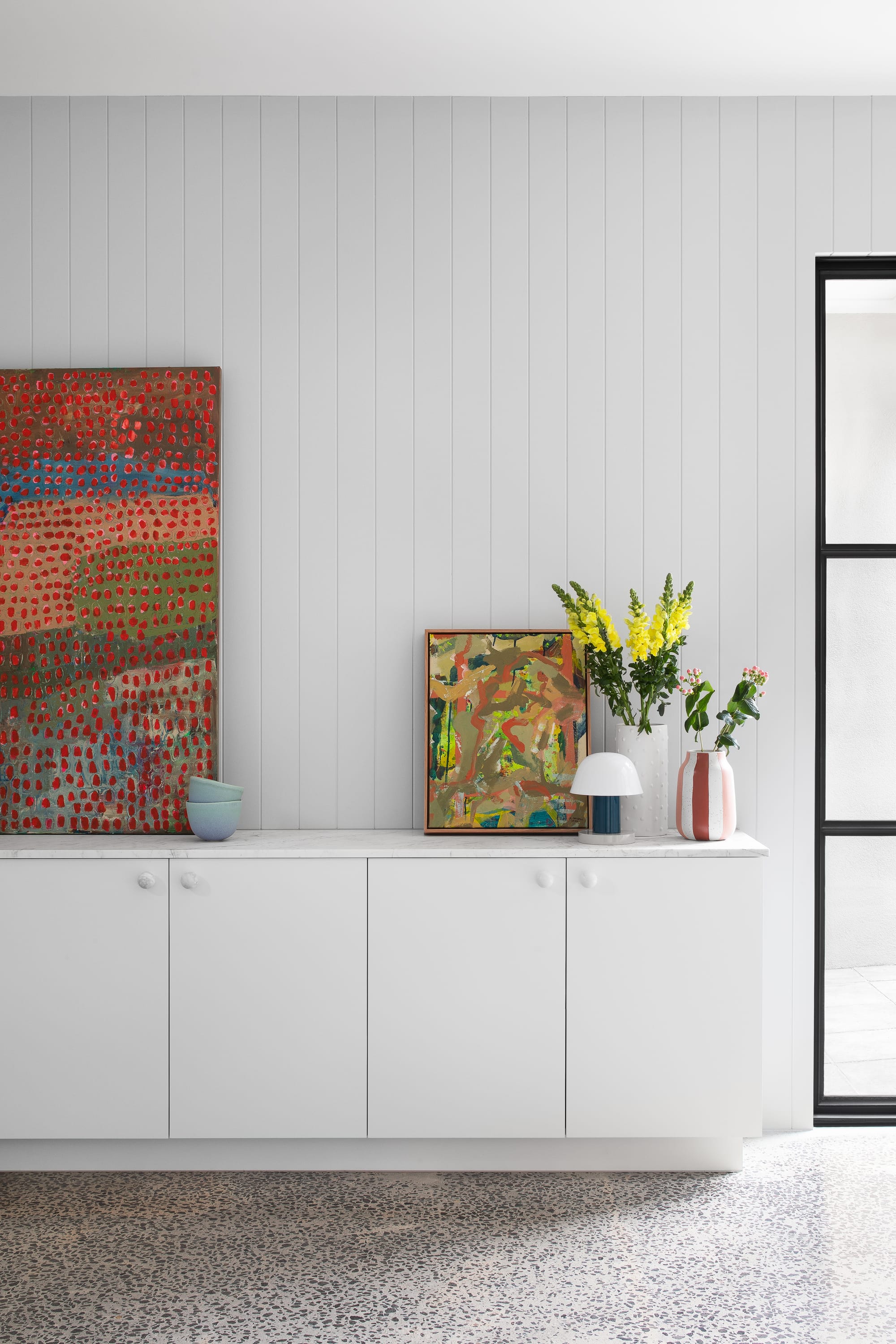 Stead House by Hannaford Design Studio. Photography by Emily Bartlett. White cabinetry with marble benchtop and four doors. Polished concrete floors. Grey clad walls.