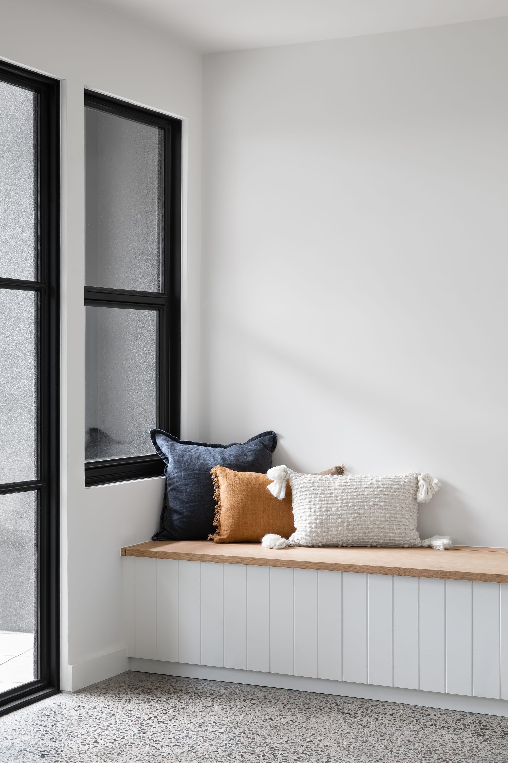 Stead House by Hannaford Design Studio. Photography by Emily Bartlett. White clad bench seat with timber top. White walls. Polished concrete floors. 