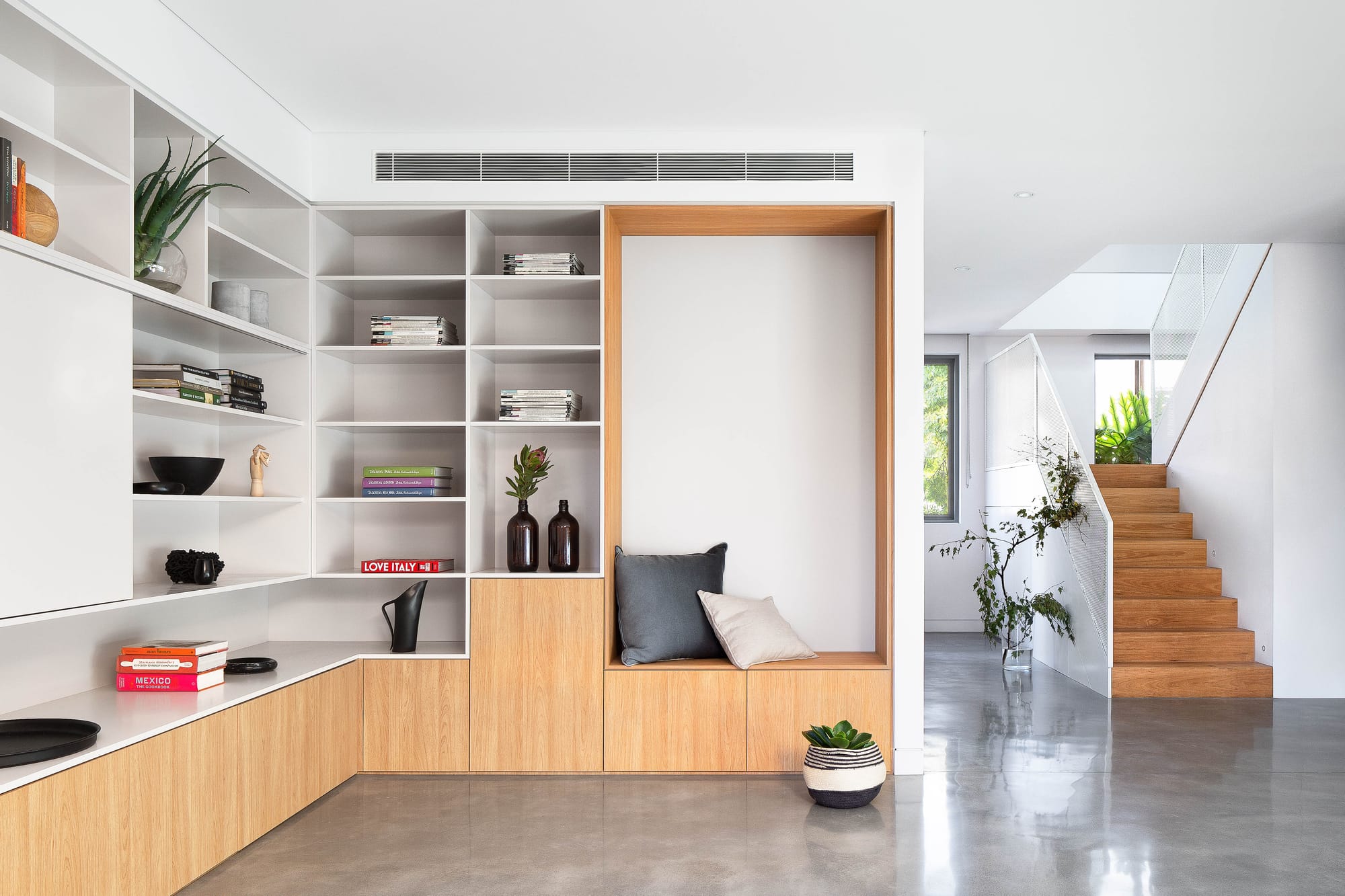 An interior shot of the renovated house showing the white and timber storage and polished concrete floor