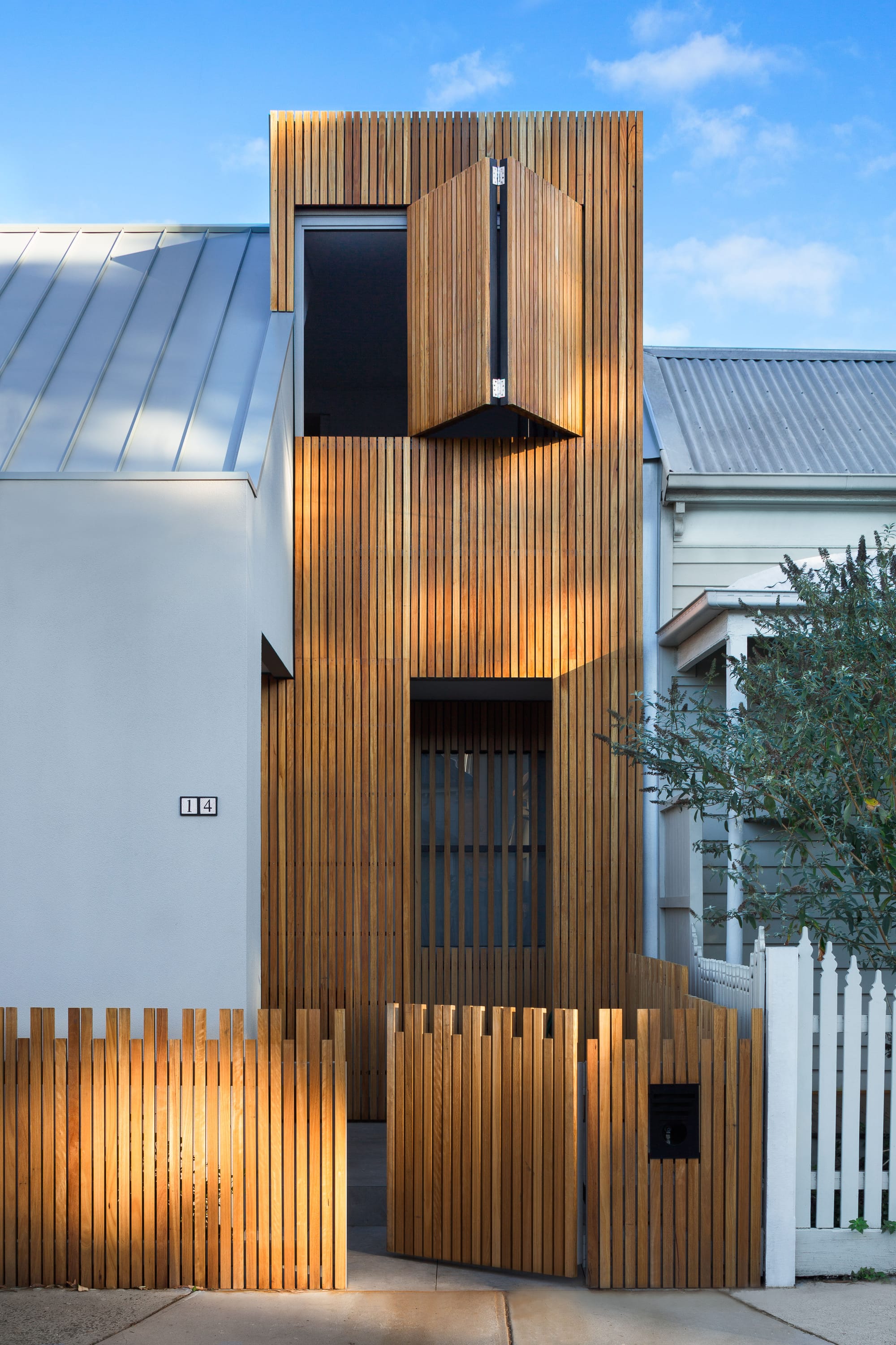 A shot from the street showing the renovated houses facade with timber and render and a timber front fence