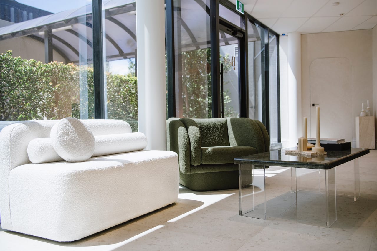 Two Made Furniture's arm chairs in white and green with a glass coffee table and light filled space